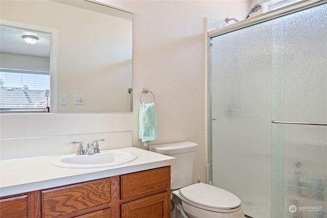 bathroom with vanity, toilet, and a shower with shower door