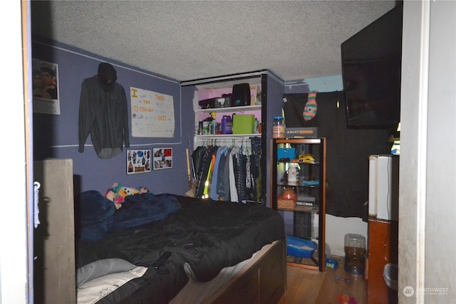 bedroom with a closet, wood-type flooring, and a textured ceiling