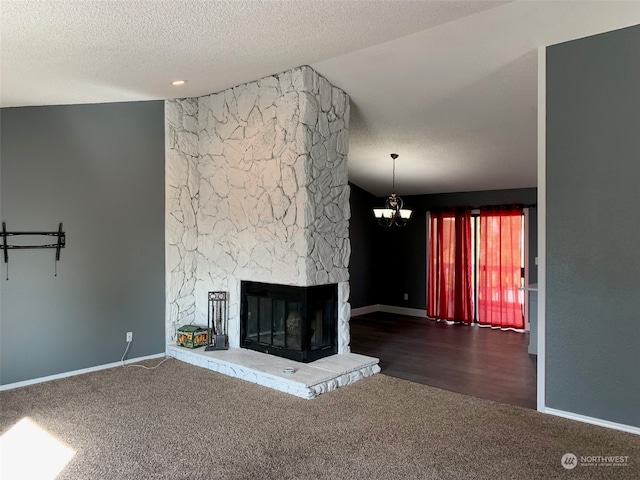 unfurnished living room featuring an inviting chandelier, a textured ceiling, a fireplace, and dark hardwood / wood-style floors