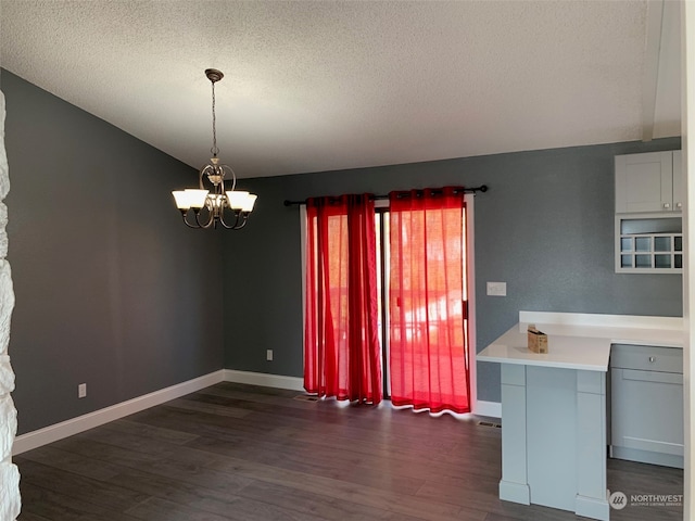 unfurnished dining area with a textured ceiling, dark hardwood / wood-style flooring, and a notable chandelier