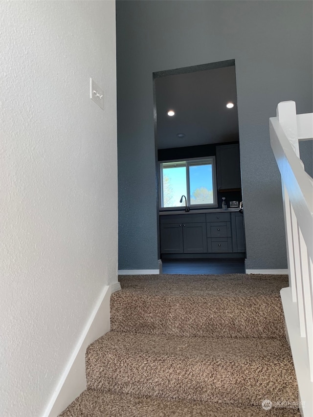 stairway featuring sink and carpet flooring