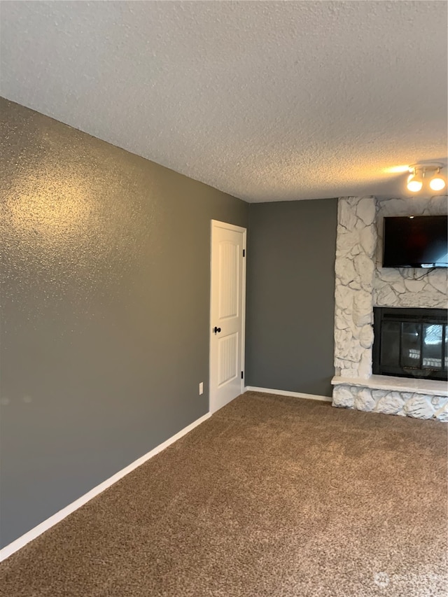 unfurnished living room featuring a textured ceiling, carpet flooring, and a stone fireplace