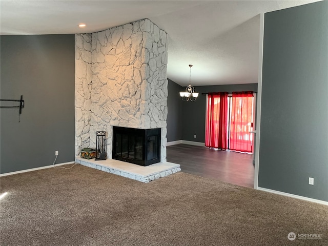 unfurnished living room featuring a stone fireplace, a notable chandelier, vaulted ceiling, and dark hardwood / wood-style flooring