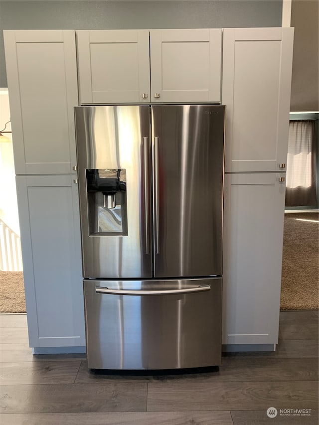 kitchen with stainless steel fridge, dark hardwood / wood-style floors, and white cabinets