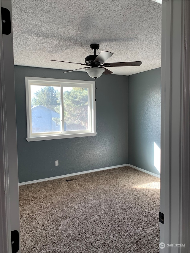 carpeted empty room with ceiling fan and a textured ceiling