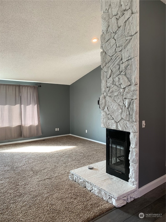 unfurnished living room featuring carpet floors, a stone fireplace, and a textured ceiling