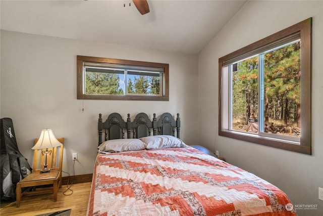 bedroom with wood-type flooring, lofted ceiling, ceiling fan, and multiple windows