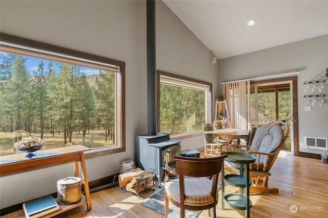 sunroom / solarium with lofted ceiling and a wood stove