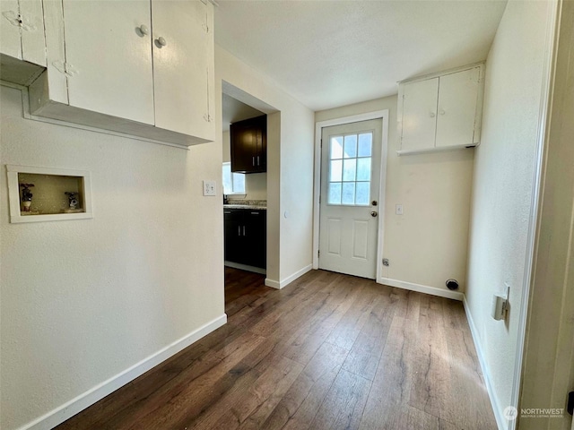 laundry room with baseboards, hookup for a washing machine, cabinet space, and dark wood-type flooring