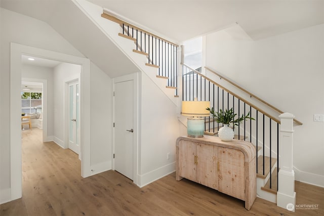 staircase with wood-type flooring and lofted ceiling