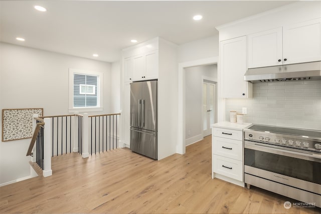 kitchen with white cabinets, stainless steel appliances, tasteful backsplash, and light hardwood / wood-style flooring