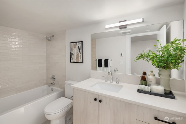 full bathroom featuring tiled shower / bath, vanity, and toilet