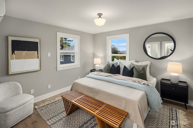 bedroom featuring multiple windows, hardwood / wood-style floors, and a wall unit AC