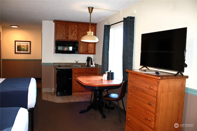 kitchen with brown cabinets, dark countertops, a sink, black microwave, and carpet floors