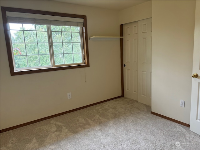 unfurnished bedroom featuring light carpet, a closet, and multiple windows