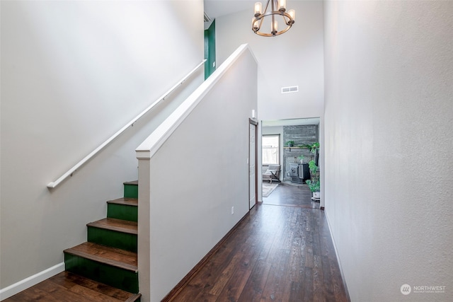 staircase featuring wood-type flooring, a towering ceiling, and a chandelier