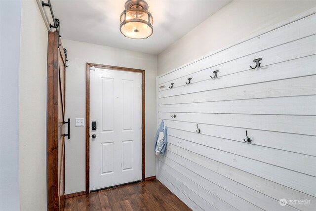 doorway to outside with dark hardwood / wood-style floors and a barn door