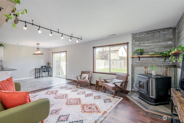 living room with a wood stove, track lighting, and dark hardwood / wood-style floors