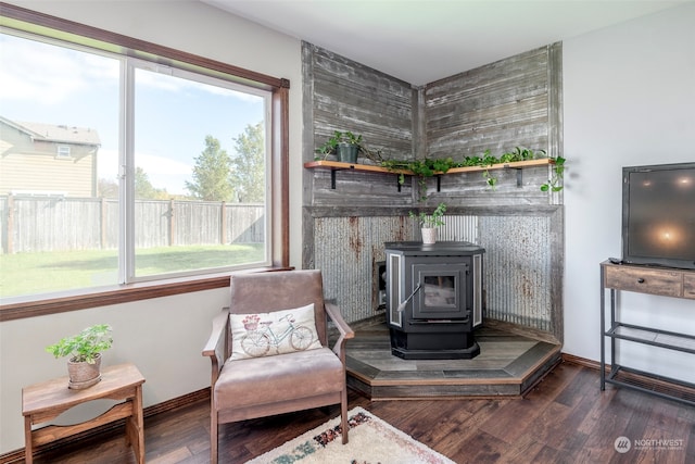 living area featuring plenty of natural light, dark hardwood / wood-style flooring, and a wood stove