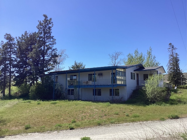 view of front facade featuring a balcony and a front lawn