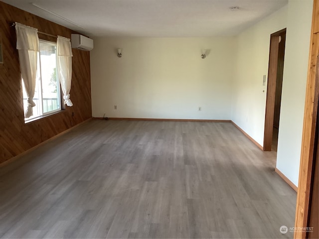 spare room with wooden walls, light wood-type flooring, and a wall mounted AC