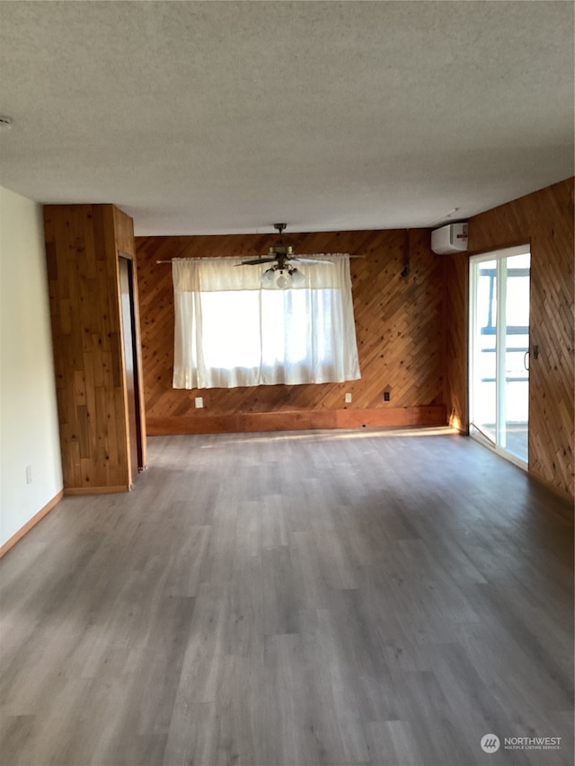 empty room with wood walls, wood-type flooring, and plenty of natural light