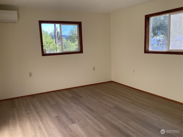 unfurnished room featuring a wall unit AC and hardwood / wood-style flooring