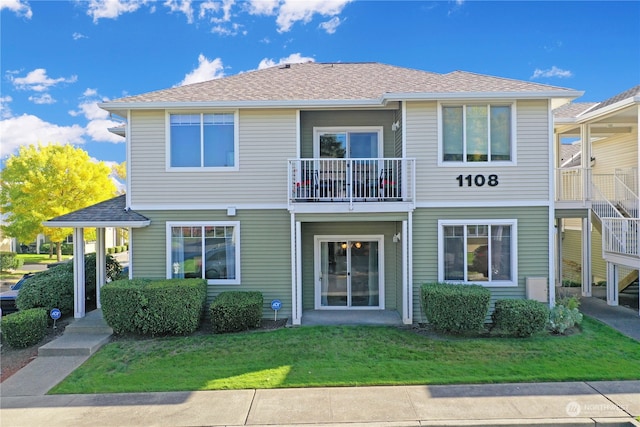 rear view of property with a lawn and a balcony