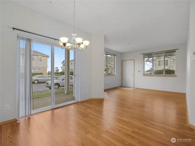 unfurnished dining area with a notable chandelier and light hardwood / wood-style flooring