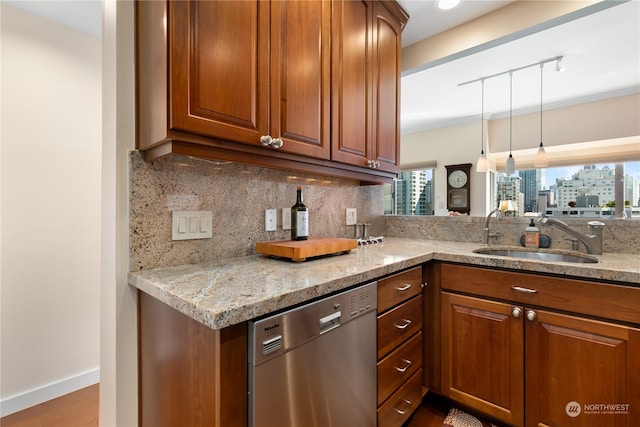 kitchen with decorative backsplash, light stone counters, hardwood / wood-style flooring, stainless steel dishwasher, and sink