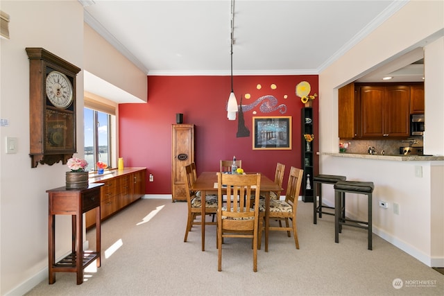 carpeted dining space featuring crown molding and rail lighting