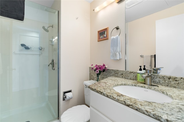 bathroom featuring vanity, toilet, and a shower with shower door