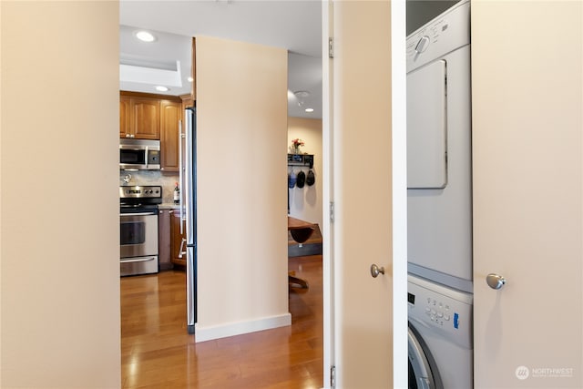 laundry room featuring light hardwood / wood-style flooring and stacked washing maching and dryer