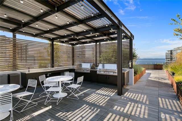 view of patio with a pergola, a water view, and area for grilling