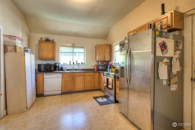 kitchen featuring sink, appliances with stainless steel finishes, vaulted ceiling, and a textured ceiling