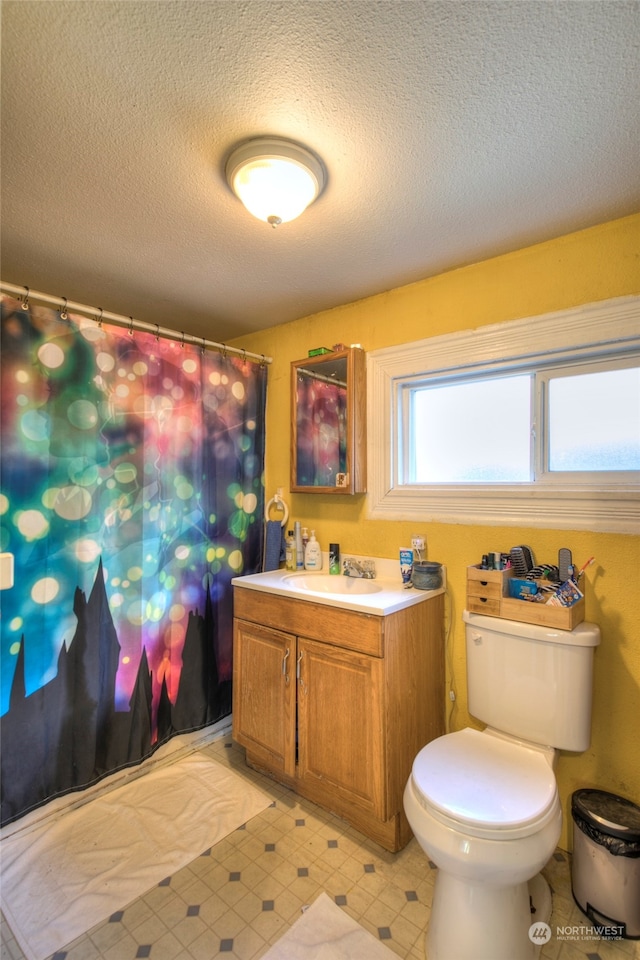 bathroom with walk in shower, vanity, toilet, and a textured ceiling