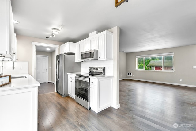 kitchen with tasteful backsplash, sink, white cabinetry, appliances with stainless steel finishes, and dark hardwood / wood-style flooring