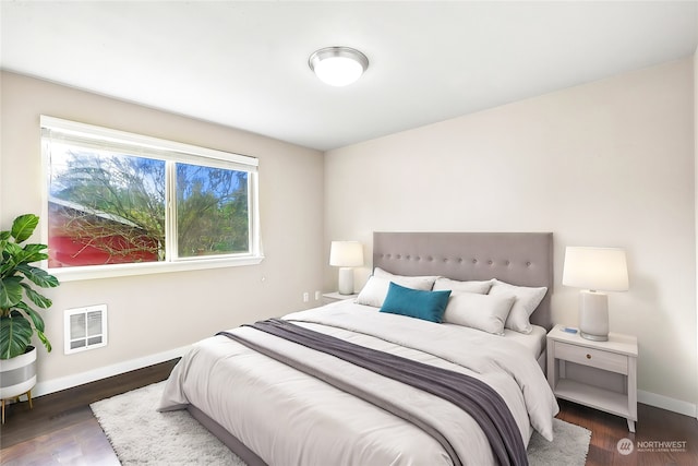 bedroom featuring heating unit, dark hardwood / wood-style flooring, and multiple windows