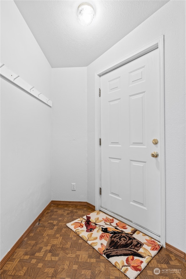 foyer entrance featuring a textured ceiling and dark parquet floors