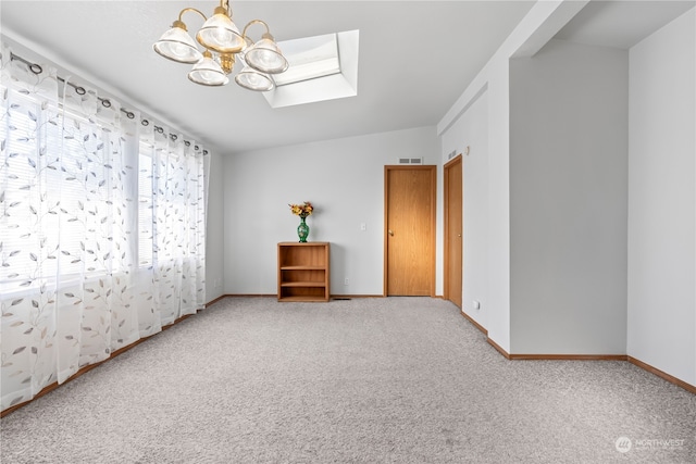 carpeted empty room featuring a notable chandelier and vaulted ceiling with skylight