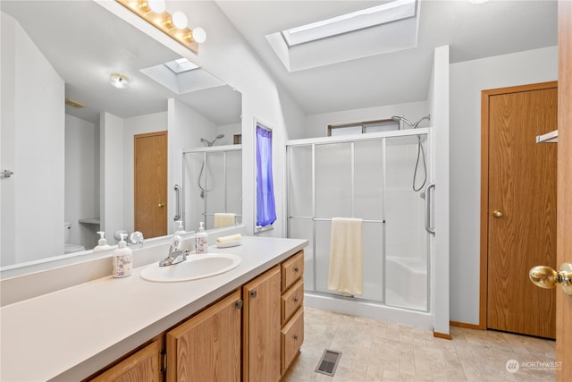 bathroom with vanity, a skylight, and a shower with door