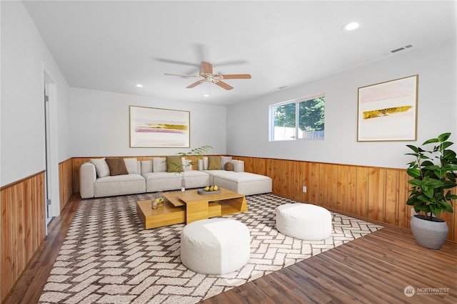 living room featuring wood walls, hardwood / wood-style floors, and ceiling fan