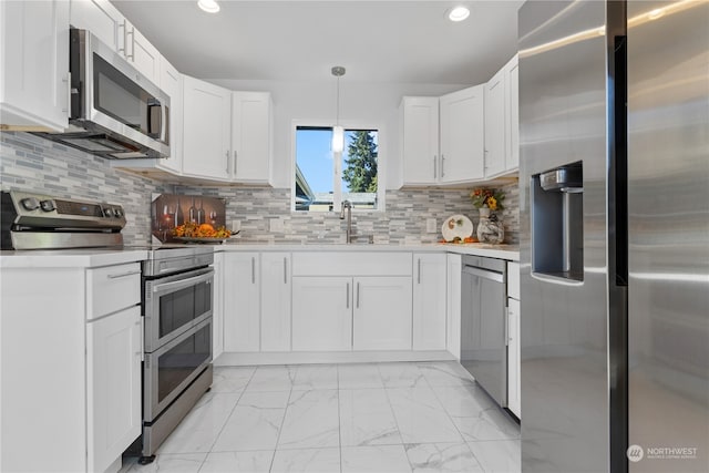 kitchen with pendant lighting, appliances with stainless steel finishes, decorative backsplash, and white cabinetry