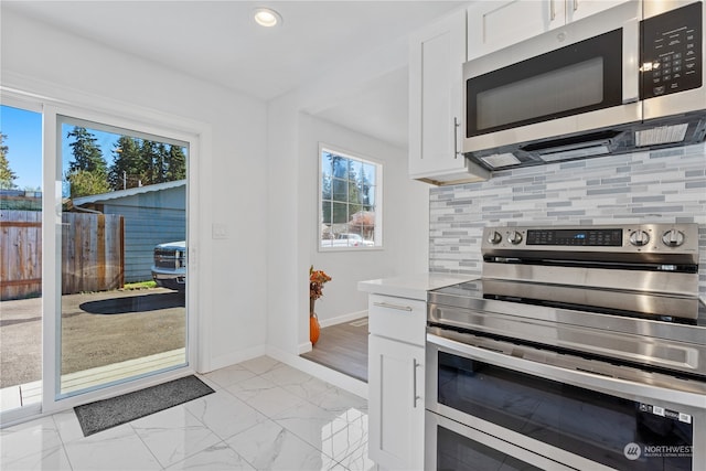 kitchen with appliances with stainless steel finishes, tasteful backsplash, white cabinetry, and plenty of natural light