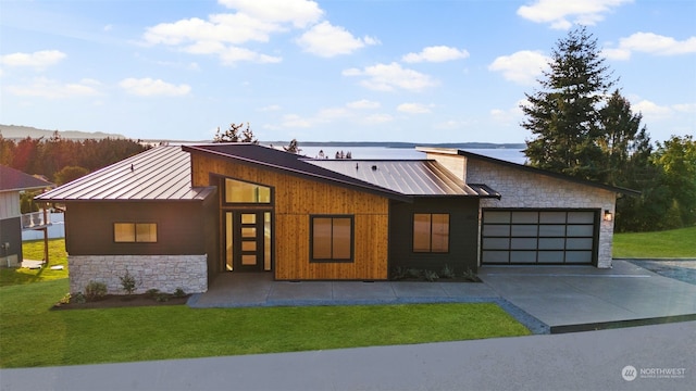 view of front facade featuring a front yard, a water view, and a garage