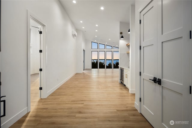 hall featuring an AC wall unit, beverage cooler, light hardwood / wood-style floors, and a wall of windows