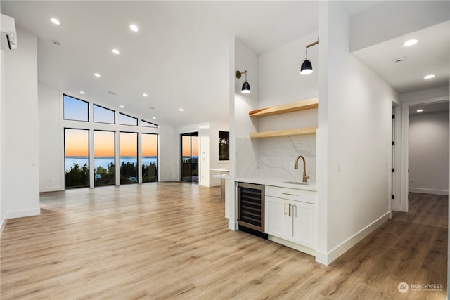 bar with wine cooler, white cabinetry, sink, and light wood-type flooring