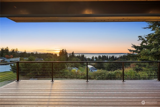 deck at dusk featuring a water view