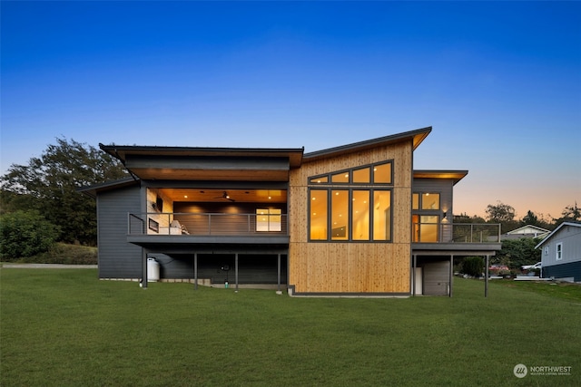 back house at dusk featuring a yard and a balcony