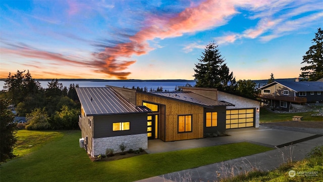 view of front facade with a yard, a water view, and a garage